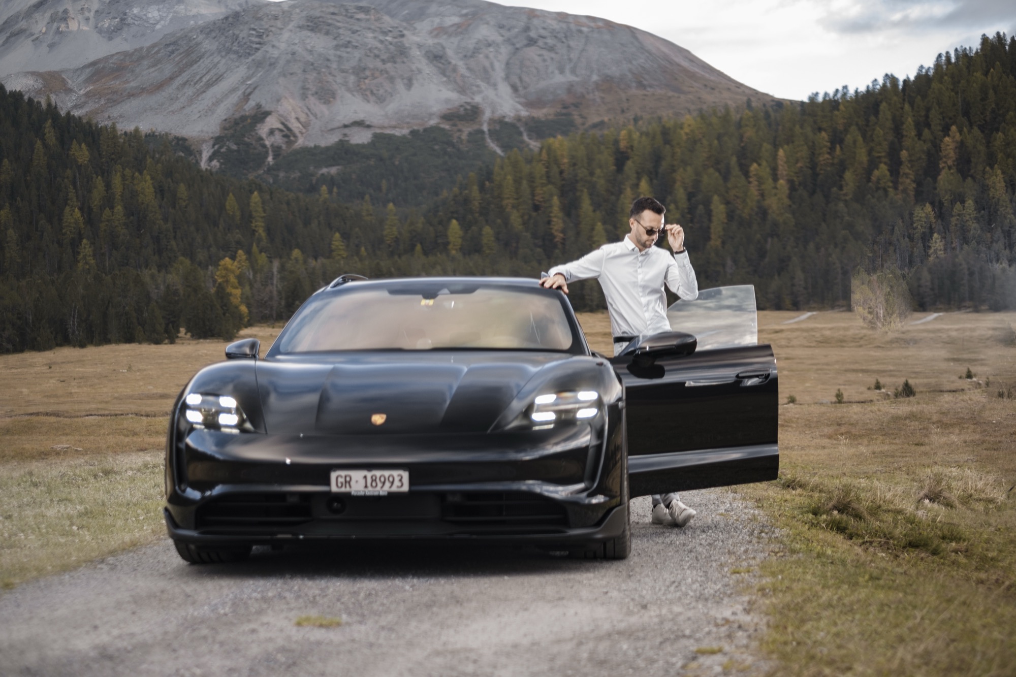 Autofotografie Porsche mit Fahrer, Tür offen, Wald- und Bergkulisse Graubünden