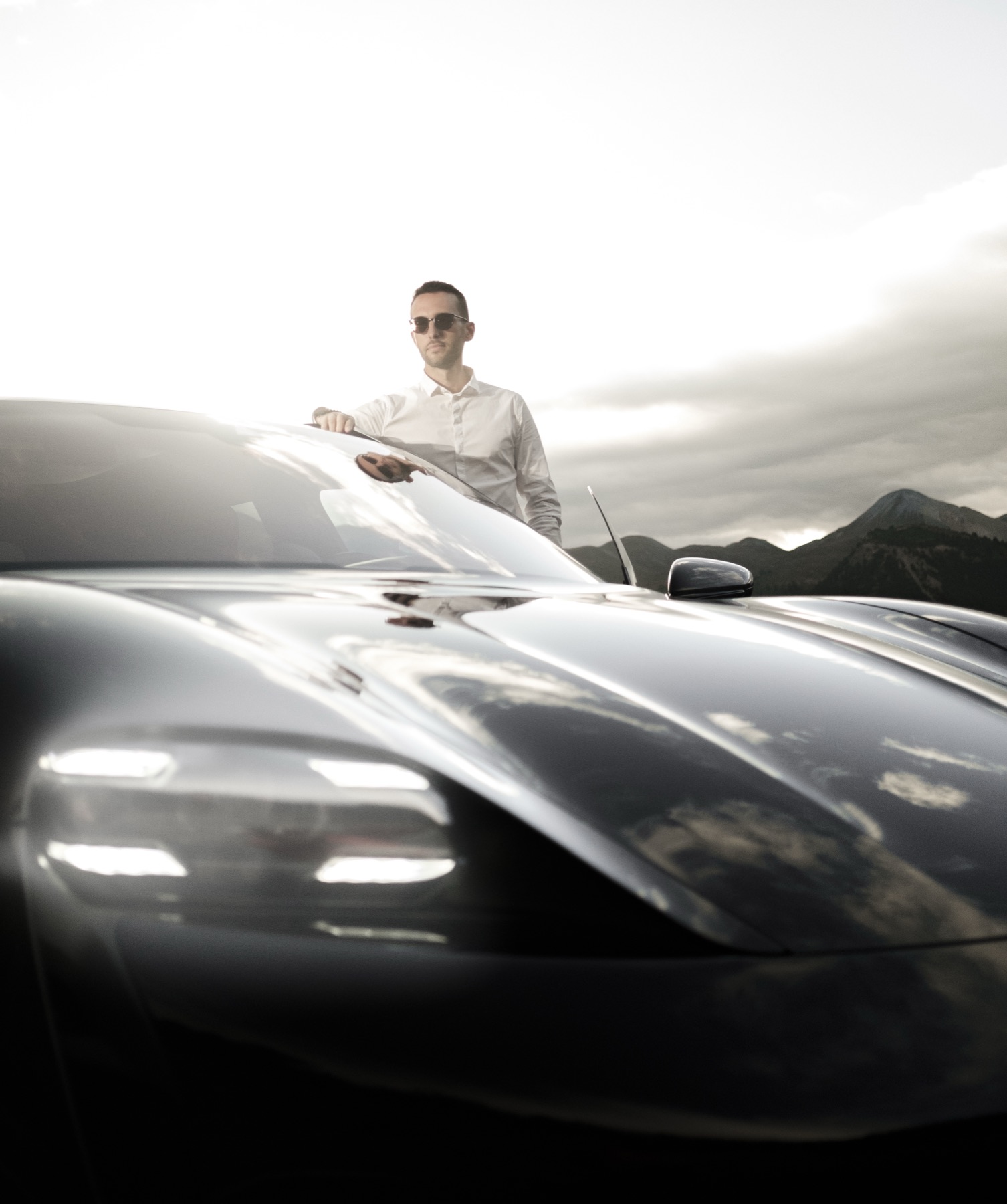 Autofotografie Porsche, Fahrer an der Motorhaube, Bergpanorama Graubünden