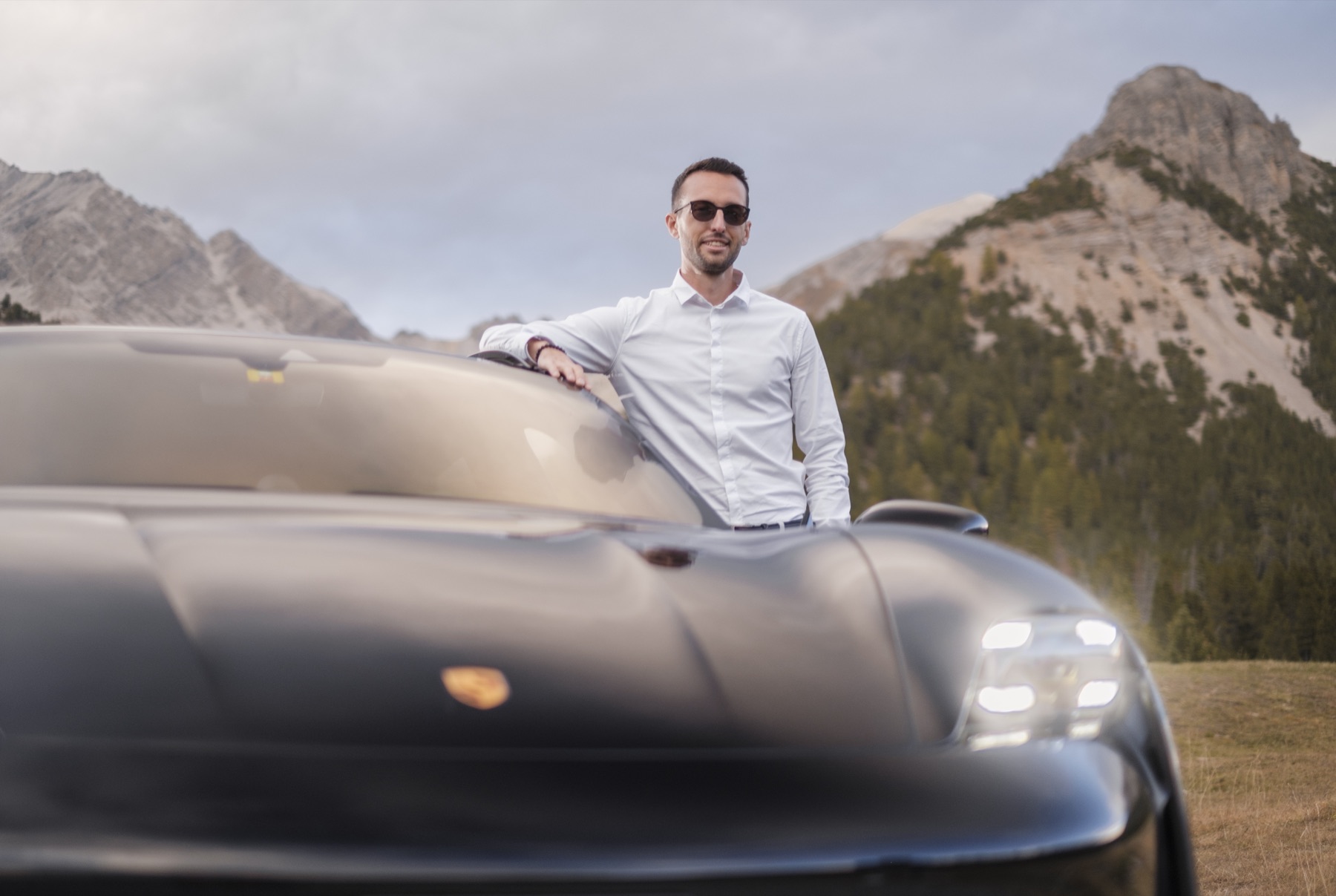 Autofotografie Porsche, Fahrer seitlich stehend vor Gipfel, Graubünden