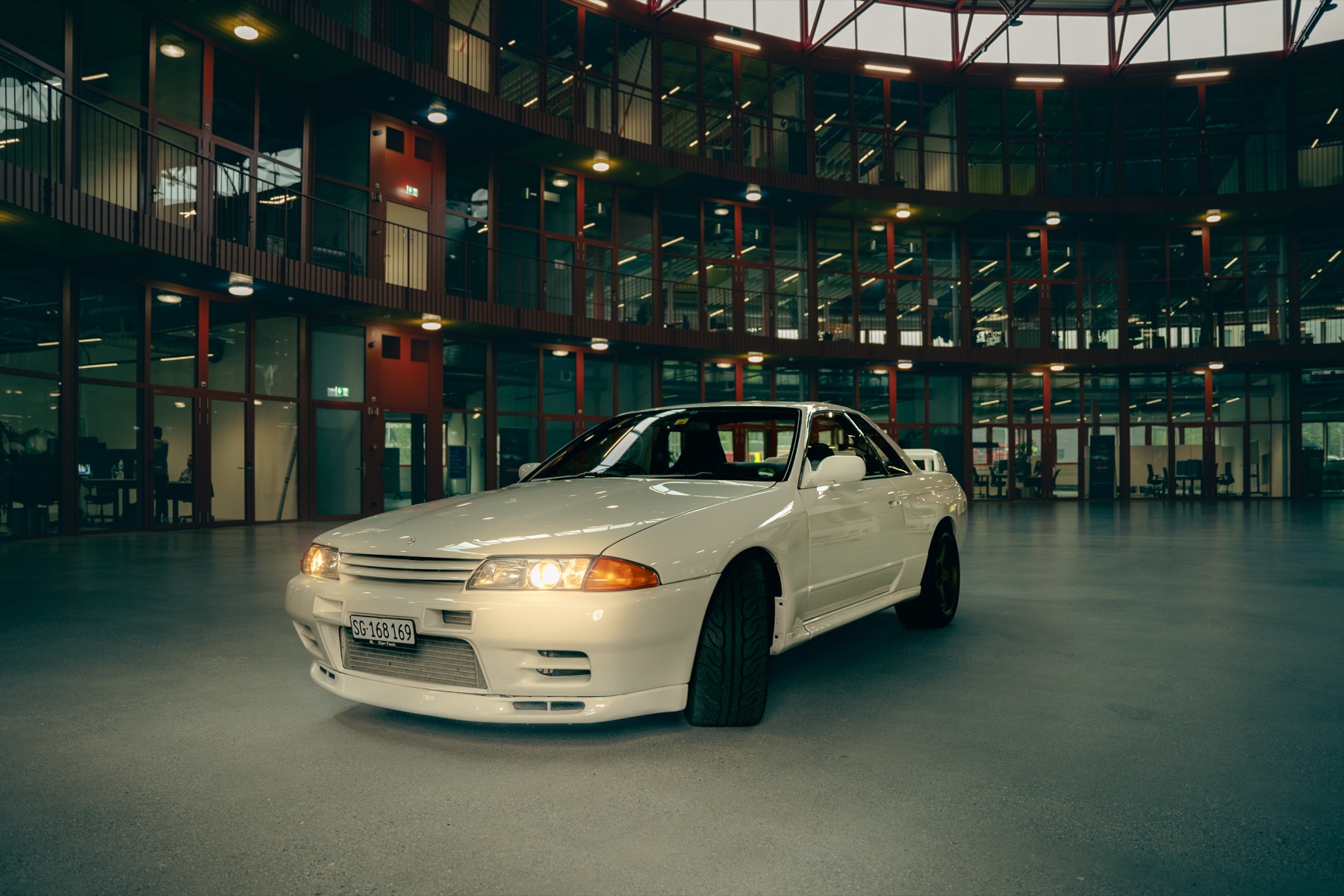 Autofotografie Nissan Skyline vor einer Glasfassade, Graubünden